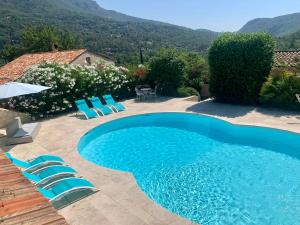 una piscina con sillas azules y una casa en Villa Kogayon, en Le Bar-sur-Loup