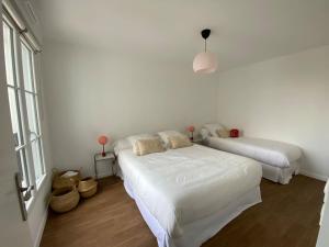 a white bedroom with two beds and a window at Disneyland Minimalist Lifestyle - 5 PAX in Serris