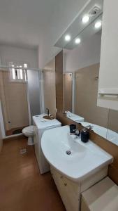a bathroom with a sink and a toilet and a mirror at Simply Meraki Gytheian apt with Panoramic Sea View in Gythio