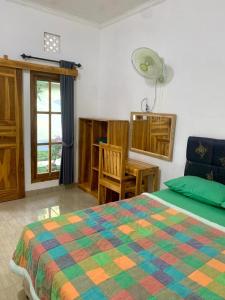 um quarto com uma cama, uma mesa e uma janela em Penginapan Sedap Malam em Lovina