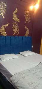 a bed with a blue headboard with gold dragons on the wall at Manavi Home Stay in Mathura