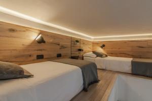 2 letti in una camera con pareti in legno di Casa Viganò a Como