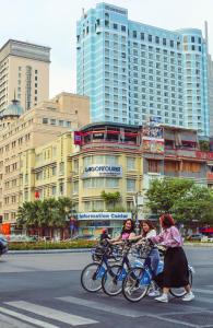 Tres chicas montando bicicletas por una calle en una ciudad en Sheraton Saigon Grand Opera Hotel, en Ho Chi Minh