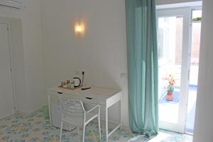 een wit bureau in een kamer met een glazen schuifdeur bij B&B Casa Angelina in Anacapri