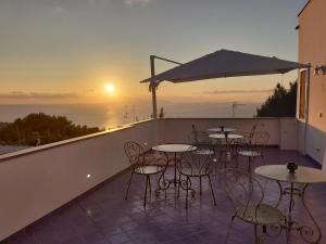 een patio met tafels en stoelen op een balkon met uitzicht op de zonsondergang bij B&B Casa Angelina in Anacapri