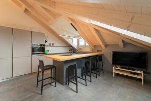 a kitchen with a bar with stools and a tv at BB Attic Suite in Cavalese