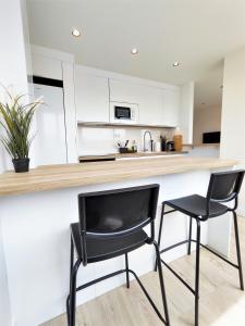 a kitchen with two black chairs at a counter at Aljarafe Central Square - by Pro Apartments in San Juan de Aznalfarache