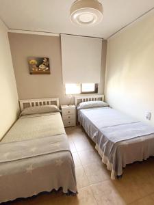 1 dormitorio con 2 camas y pared blanca en Acogedor apartamento en la Playa. Urbanización La Felicidad. Las Marinas en Dénia