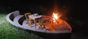 a table and chairs next to a fire pit at Recanto do Leão in Alagoa