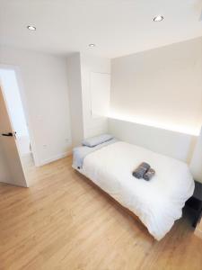 a bedroom with a white bed and a wooden floor at Aljarafe Central Square - by Pro Apartments in San Juan de Aznalfarache