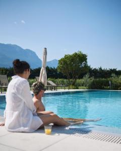 una mujer y un hombre sentados junto a una piscina en Hotel Al Maso, en Riva del Garda