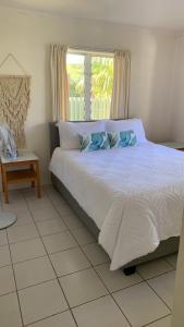 a bedroom with a white bed with a window at Konini Villa in Rarotonga