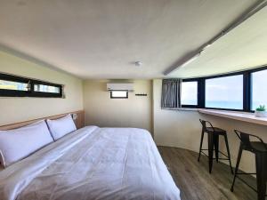 um quarto com uma cama e um bar com janelas em 55 Hearts Gathering backpacker & B&B em Nangan