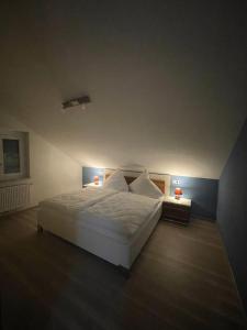 een slaapkamer met een groot wit bed met 2 lampen bij Ferienwohnung MaRe in Oberteuringen