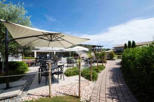 een patio met tafels en stoelen en een parasol bij Lake Garda Resort in Moniga