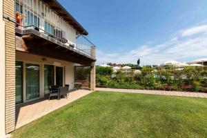 een huis met een tuin met een patio en gras bij Lake Garda Resort in Moniga