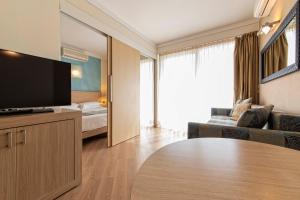 a living room with a television and a couch and a bed at Lake Garda Resort in Moniga