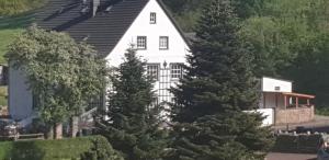 a white house with trees in front of it at Ferienwohnung im Landhausstiel in Winkel