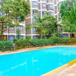 une grande piscine bleue en face d'un bâtiment dans l'établissement Lux Suites Green City Gardens Syokimau, à Nairobi