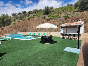 een patio met een parasol, een zwembad en stoelen bij VILLA GABRIEL in Canillas de Albaida