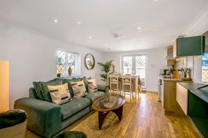 Una sala de estar con un sofá verde y una cocina. en The Annex - Unparalleled Beach Front Luxury Accommodation - Private South West Facing Patio Area - Pet Friendly - Sky - Netflix - Super Fast WI-FI - Stones Throw To The Beach, en Southbourne