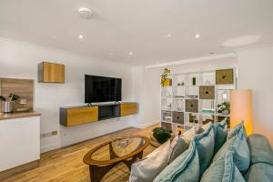 uma sala de estar com um sofá azul e uma televisão em The Annex - Unparalleled Beach Front Luxury Accommodation - Private South West Facing Patio Area - Pet Friendly - Sky - Netflix - Super Fast WI-FI - Stones Throw To The Beach em Southbourne