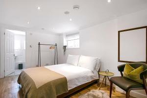 Un dormitorio blanco con una cama y una silla. en The Annex - Unparalleled Beach Front Luxury Accommodation - Private South West Facing Patio Area - Pet Friendly - Sky - Netflix - Super Fast WI-FI - Stones Throw To The Beach, en Southbourne