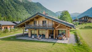 Cabaña de madera con terraza grande y montañas al fondo en Hevea, en Chamonix-Mont-Blanc