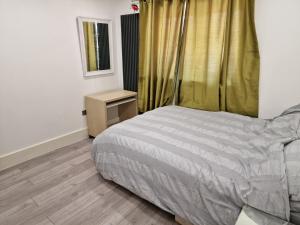a bedroom with a bed and a table and a window at Studio Flat with kitchen and toilet included in Dagenham