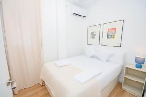 - une chambre blanche avec un lit et deux photos sur le mur dans l'établissement For You Rentals Cozy and charming 3-bedroom apartment in Madrid ASR18, à Madrid