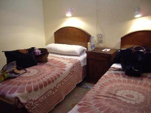 a hotel room with two beds and a dresser at Memnon Hotel in Aswan