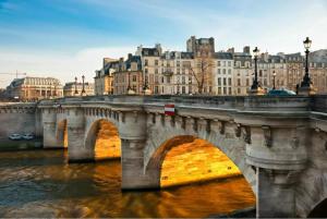 a bridge over a river with a city in the background at Unforgettable Stay in the Heart of Paris in Paris
