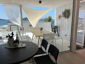 a dining room with a table and chairs on a balcony at BUQEZ ECO RESORT - Beach Villas 2 and 8 - Seaview, new wifi! in Drage