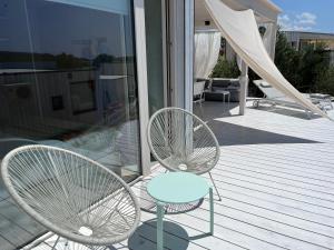 two white chairs and a table on a deck at BUQEZ ECO RESORT - Beach Villas 2 and 8 - Seaview, new wifi! in Drage