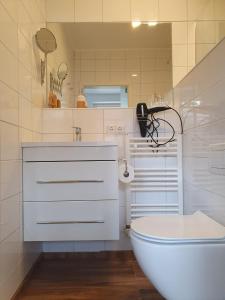 ein Badezimmer mit einem weißen Waschbecken und einem WC in der Unterkunft FEWO am Dele Park in Wilhelmshaven