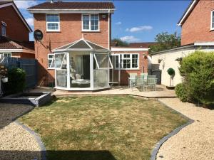 a garden with a conservatory in front of a house at Double bed Parking Internet Coffee Garden Patio TV Quiet Close to main bus route B98 9NH in Beoley