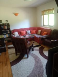 a living room with a red couch and a rug at Apartmani Rocen in Žabljak