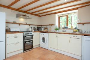 a kitchen with white cabinets and a washer and dryer at Whitley Farm Dairy in Northleigh