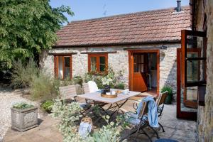 a table and chairs in front of a stone cottage at Whitley Farm Dairy in Northleigh