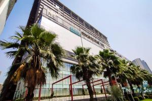 a large building with palm trees in front of it at Taj Suites & Studios-Top Place Couple Friendly Stay at Luxury Gaur City Mall #Movie, #Food Court #Shopping in Ghaziabad