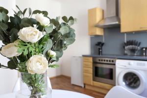 eine Vase weißer Rosen auf einem Tisch in einer Küche in der Unterkunft Modern Apartment, 3 min to "U3 Neubaugasse" in Wien