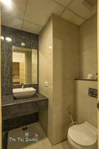 a bathroom with a sink and a toilet and a mirror at Taj Suites & Studios-Top Place Couple Friendly Stay at Luxury Gaur City Mall #Movie, #Food Court #Shopping in Ghaziabad