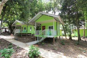 a green house with a porch in the woods at Koh Phayam Greentawan Resort in Ko Phayam