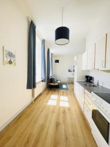 aday - Blue light suite apartment in the center of Hjorring في يورينغ: مطبخ مع خزائن بيضاء وأرضية من الخشب الصلب