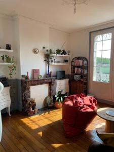 een woonkamer met een open haard en een rode poef bij Appartement Haussmannien in Épernay