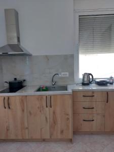 cocina con armarios de madera, fregadero y ventana en Bebas apartment in the centre, en Sarandë