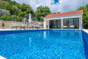 a swimming pool with blue water in front of a house at Villa Konavoski Miri in Gruda