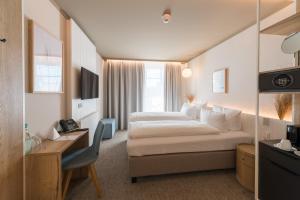ein Hotelzimmer mit einem großen Bett und einem Schreibtisch in der Unterkunft Hafenhotel zu Putbus in Putbus