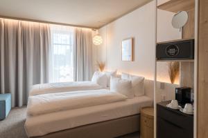 a bedroom with a bed with white sheets and a window at Hafenhotel zu Putbus in Putbus