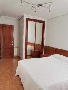 - une chambre avec un lit blanc et un miroir dans l'établissement apartamento Puente, à Suances